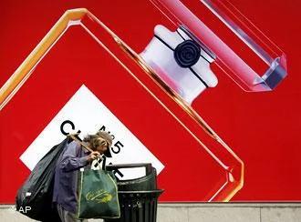 A scavenger looks for plastic bottles from a public trash bin with a propaganda of a perfume as background Wednesday Sept.3,2008 in Shanghai, China. China may raise its poverty threshold to double the number of people eligible for government help as income gaps reach their widest level in three decades, state media reported Wednesday.(AP Photo/Eugene Hoshiko)