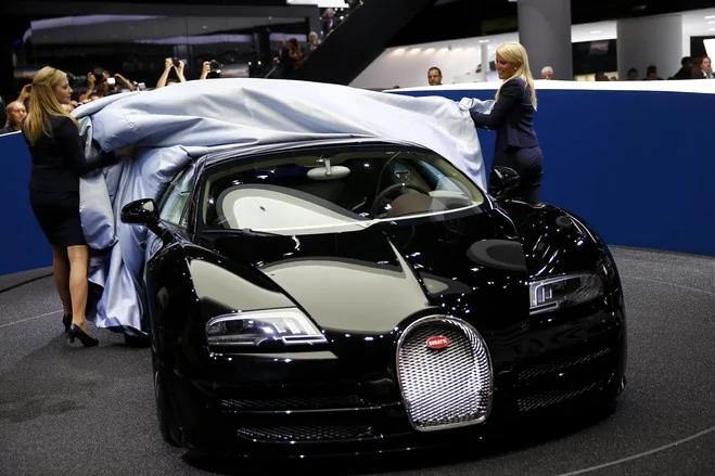 周二，车模们揭开新款布加迪“Jean Bugatti”的车罩。