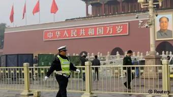 A policeman walks past in front of the giant portrait of the late Chinese Chairman Mao Zedong as other policemen clean up after a car accident at the Tiananmen Square in Beijing, October28,2013. Chinese police on Monday evacuated Beijing