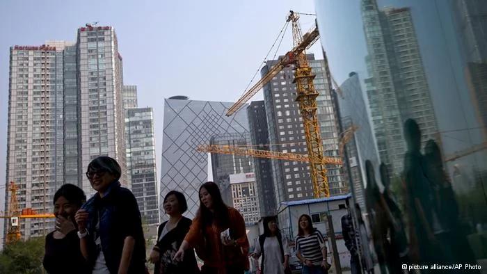 Women walk past a construction site and office buildings at the Central Business District during their lunch break in Beijing, China Tuesday, Oct.8,2013. Chinese President Xi Jinping sought Monday to reassure Asian business and political leaders that his country only aspires to peace and that he is confident its economic growth will remain robust despite a recent slowdown.(AP Photo/Andy Wong)    