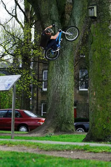 组图：小伙骑自行车爬墙上树展示绝技