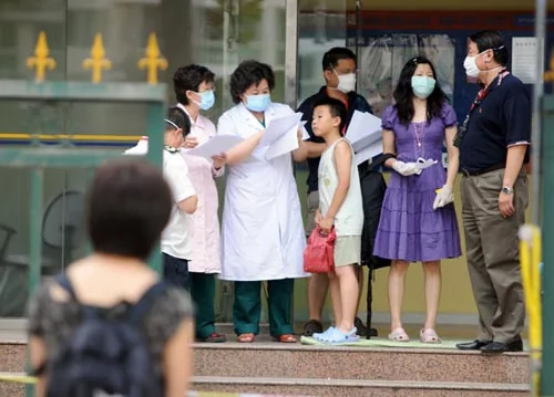 2009年7月1日，北京市卫生局通报，朝阳区南湖中园小学发生一起学校聚集性发热疫情，16个发热学生中已有7人被确诊为甲型H1N1流感病例。该校学生被转移至酒店隔离观察。图：工作人员正在给被转移的小学生登记