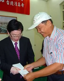 中共宗教局長王作安（左）在拜訪台北清真寺後，收到法輪功學員（右）送的訴狀，王認為是禮物，道謝收下。