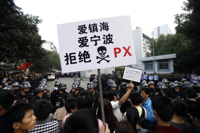 中央和地方政府现在担心的是，作为中国新兴的“邻避”运动的一部分，类似的群体事件可能再次发生。图为一名抗议者高举“爱镇海、爱宁波、拒绝PX”的标语。镇海是石化厂扩建项目所在的区。