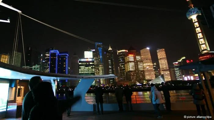 Auf dem Aussichtsdeck eines Ausflugschiffes stehen am Donnerstag(24.11.2011) Menschen vor der leuchtenden Skyline der chinesischen Metropole Shanghai. Die Hafenstadt ist das wirtschaftliche Zentrum der Volksrepublik. Der«Drachenkopf am Jangtse» zählt mit18 Millionen Einwohnern zu den zehn größten Städten der Erde. Foto: Heiko Lossie dpa/lsw