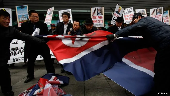 Activists from an anti-North Korea civic group try to tear a North Korea flag during a rally against North Korea's nuclear test near the U.S. embassy in central Seoul February12,2013. North Korea conducted its third nuclear test on Tuesday in defiance of U.N. resolutions, angering the United States and Japan and prompting its only major ally, China, to call for calm. REUTERS/Kim Hong-Ji(SOUTH KOREA- Tags: CIVIL UNREST POLITICS)

