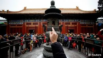 A man tries to throw an coin onto the top of an iron tower for good fortune on the first day of the Chinese Lunar New Year at Yonghegong Lama Temple, in Beijing February10,2013. The Lunar New Year, or Spring Festival, begins on February10 and marks the start of the Year of the Snake, according to the Chinese zodiac. REUTERS/Jason Lee(CHINA- Tags: SOCIETY RELIGION)