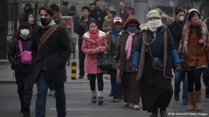 Pedestrians cross a street, some wearing face masks, during polluted weather in Beijing on January13,2013. Dense smog shrouded Beijing, with pollution at hazardous levels for a second day and residents advised to stay indoors, state media said. AFP PHOTO/ Ed Jones(Photo credit should read Ed Jones/AFP/Getty Images)