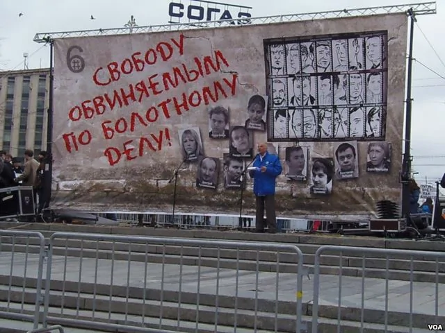 一名男子在莫斯科支持政治犯集会上演讲。他身后的背景是被关押和流亡的政治犯照片，幕墙上的字是释放去年5月6日示威的被捕人士。（美国之音白桦拍摄）