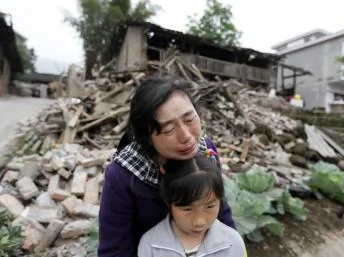 雅安一婦女在地震廢墟前痛哭。