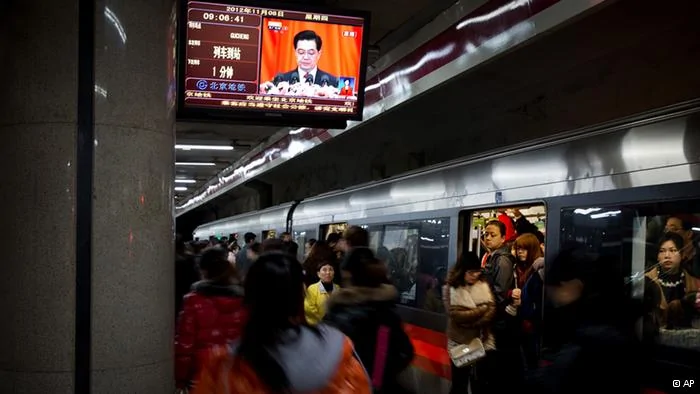 Commuters walk past a TV showing a live broadcasting of Chinese President Hu Jintao's remarks during the opening session of the18th Communist Party Congress, at a subway station in Beijing, China, Thursday, Nov.8,2012. Preparing to hand over power after a decade in office, China's President Hu Jintao called Thursday for sterner measures to combat official corruption that has stoked public anger while urging the Communist Party to maintain firm political control.(Foto:Andy Wong/AP/dapd).