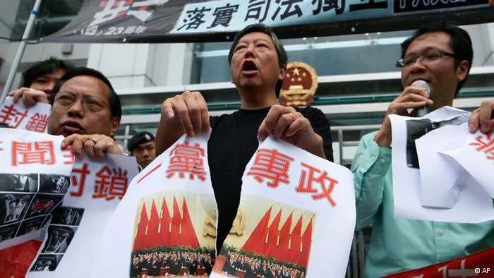 Pro-democracy activists tear a picture of the18th Communist Party Congress held in Beijing with Chinese writing reading One party rule in China outside the Chinese central government's liaison office in Hong Kong Thursday, Nov.8,2012. Protesters demanded the Chinese government stop one party rule in China on the first day of a weeklong party congress in Beijing.(Foto:Kin Cheung/AP/dapd).