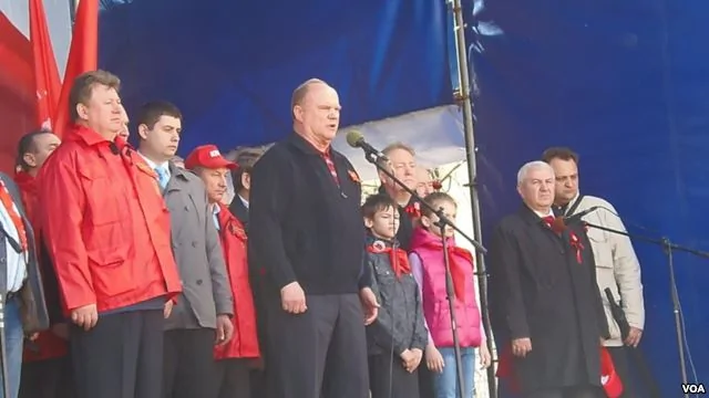 共產黨議員卡申（身穿紅衣）同俄共領袖久加諾夫（講話者）在5月1日莫斯科共產黨遊行集會上（美國之音白樺拍攝）