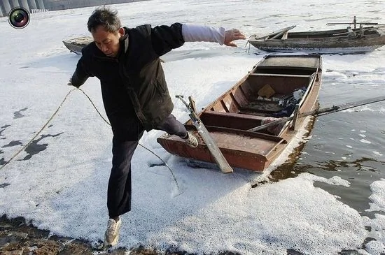 合肥一条惨遭污染的河流，一名渔民正从船上往岸上跳