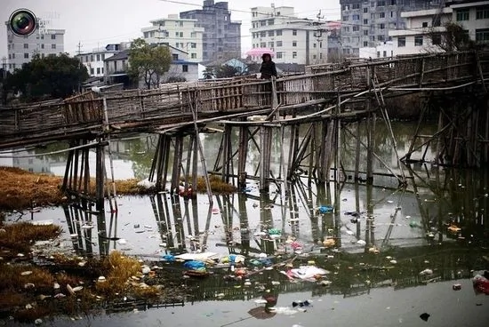 2011年2月18日，浙江温州郊区一条惨遭污染的河流，一名妇女在桥上走过。