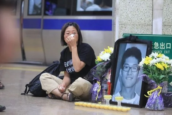 马跃母亲在安定门地铁站内摆上儿子的照片和菊花祭奠逝去的儿子马跃