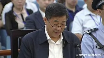 In this image taken from video, Former Chinese politician Bo Xilai reads in a court room at Jinan Intermediate People's Court in Jinan, eastern China's Shandong province, Sunday, Aug.25,2013. Bo on Sunday sought to discredit his former top aide as a lying, unreliable witness as the ousted leader denied criminal responsibility in the country's messiest political scandal in decades.decades.(AP Photo/CCTV via AP Video) CHINA OUT, TV OUT
***FREI FÜR SOCIAL MEDIA***