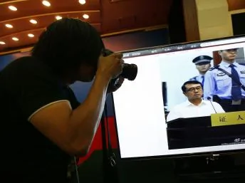 攝影師在山東濟南中級人民法院門外對著視頻拍照。2013年8月24日。