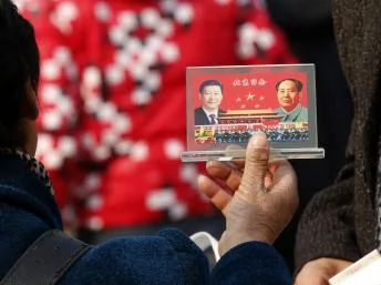 2013年１１月８日北京天安门广场上一名商贩向游客展示纪念品。