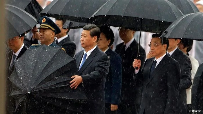 China's President Xi Jinping takes down his umbrella next to Premier Li Keqiang(R) before they and other Chinese Communist Party top leaders stand in silent tribute as it rains during a tribute ceremony at the Monument to the People's Heroes, on the64th anniversary of the founding of the People's Republic of China, in Beijing October1,2013. China celebrates its National Day on Tuesday. REUTERS/Jason Lee(CHINA- Tags: POLITICS ANNIVERSARY)
