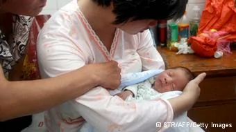 This picture taken on August5,2013 shows a woman surnamed Dong(C) holding her newborn baby surrounded at a hospital in Fuping County, central China's Shanxi province. A baby boy allegedly sold by the doctor who delivered him in China has been reunited with his parents, state media reported on August6, in a case highlighting the problem of child trafficking. CHINA OUT AFP PHOTO(Photo credit should read STR/AFP/Getty Images)