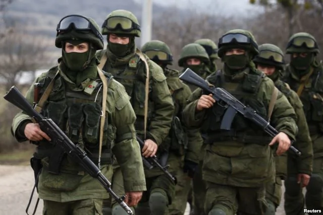 被认为是俄罗斯军人的武装分子行走在克里米亚的乌克兰军营外面