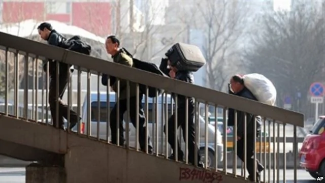 2010年3月2日在北京打工的農民扛着行李在北京車站附近走上一架天橋