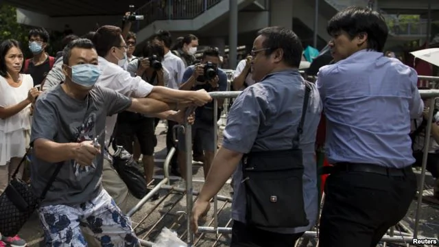 香港反对占中者（左）手持钳子，剪断捆绑路障的铁丝。这些路障是占中者设置的。（2014年10月）
