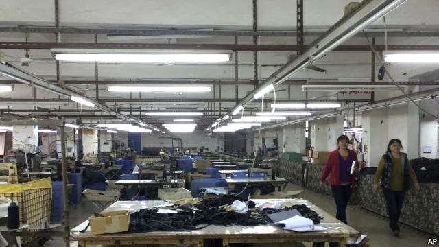 中國廣東省中山市南朗鎮翠亨制包廠工人罷工，幾名工人走過車間裡處於停工狀態的工作檯，2015年3月26日（資料圖）