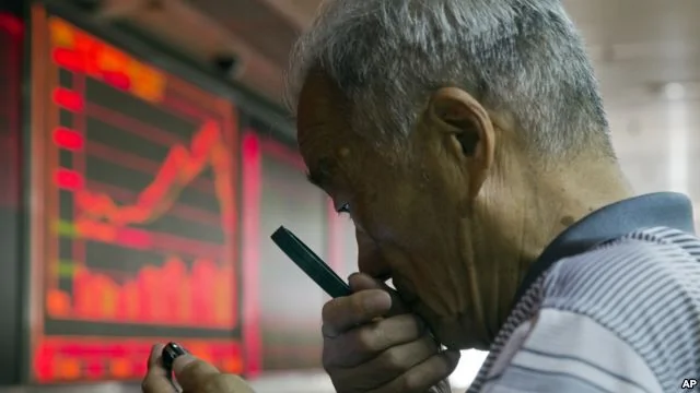 一中国股民7月9日在北京一家交易厅用放大镜查看手机上的股市价格。