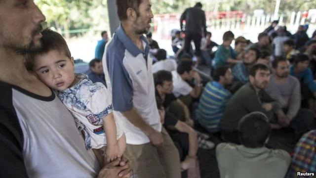 在泰国-马来西亚边界被拘留的一个疑似来自新疆的维吾尔人抱着孩子在临时收容所里（2014年3月14日）