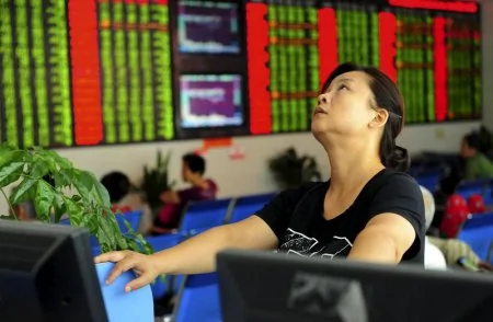 An investor looks up in front of an electronic board showing stock information at a brokerage house in Fuyang, Anhui province, China August21,2015. REUTERS/China Daily