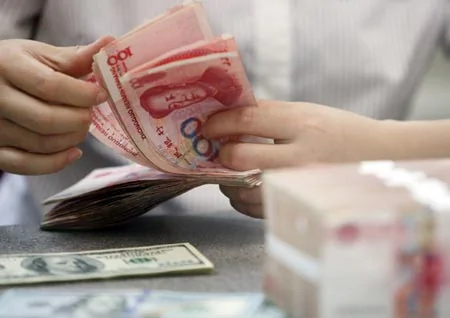 A clerk counts renimnbi and US dollar banknotes at a bank in Shandong province, Aug.12.(File photo/Xinhua)