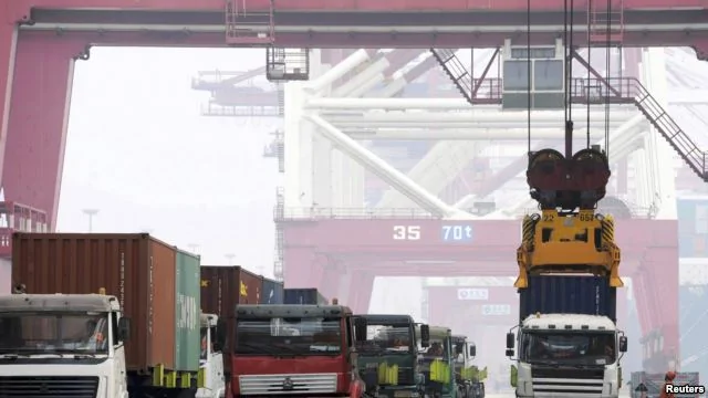 在中國青島港，工人用吊車把貨櫃吊起來裝船（2015年10月13日）