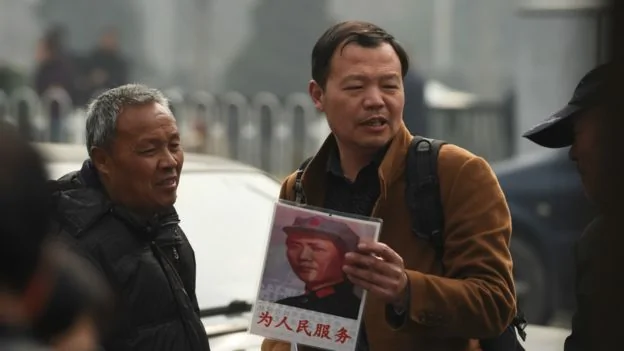 一個手持毛澤東畫像的北京市民
