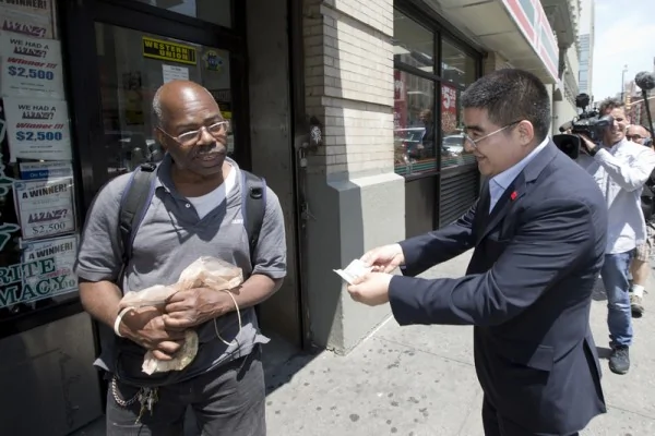 2014年6月24日，美国纽约，大陆商人陈光标在纽约街头赠送百元纸币，有的人拒绝了他递过来的钱。*