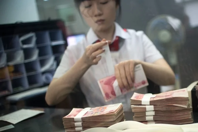 A worker at an Industrial and Commercial Bank of China Ltd(ICBC) branch counts money as she serves a customer on Sept.24,2014.(JOHANNES EISELE/AFP/Getty Images)
