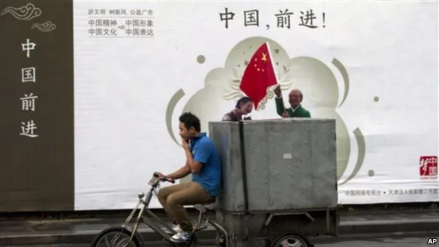 2013年7月15日北京送货自行车驶过宣传广告牌“中国，前进！”