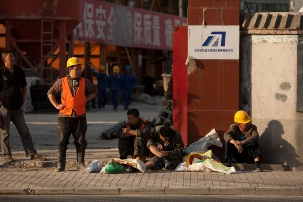 由于西方市场需求不振，和东南亚工厂的兴起，双重挤压、冲击了中国工厂，工厂倒闭、外移，失业工人将引发严重社会问题。图为2012年5月，北京市某工地工人在门口休息的场面。（Ed Jones/AFP/GettyImages）