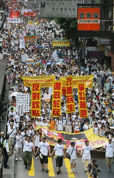 2005年七一大遊行的主題為「反對官商勾結，爭取全面普選」。圖為2005年7月1日，香港，參加遊行。（Richard A. BROOKS／AFP)