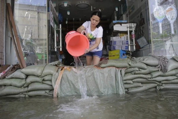 2016年7月7日，湖北武汉，道路淹水，民众在门口堆上沙包。(Wang He/Getty Images)