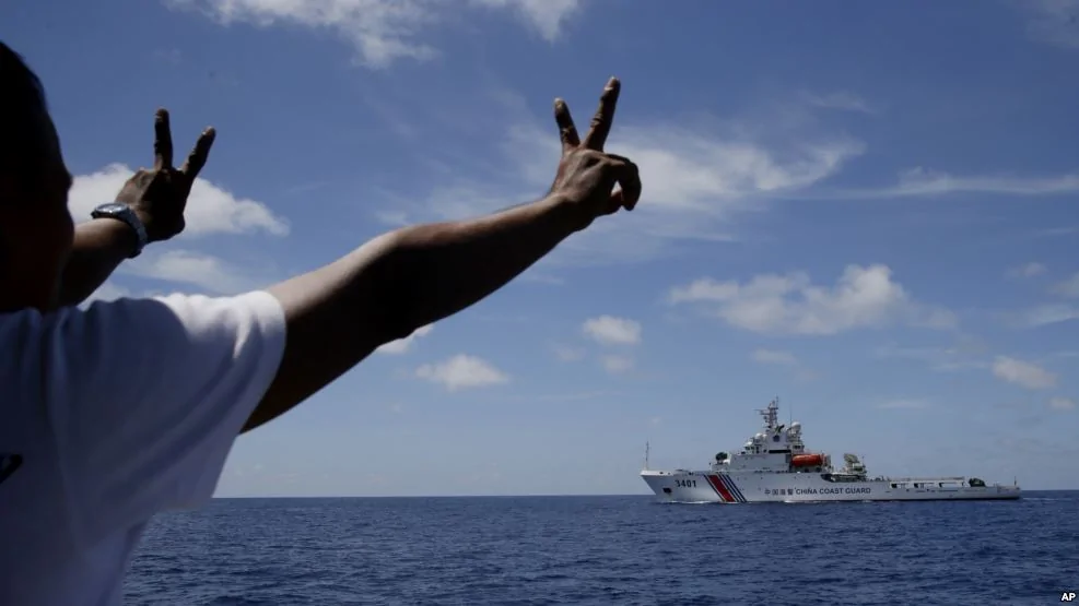 菲律宾船上人员向阻止他们进入南中国海第二托马斯浅滩（仁爱礁）的中国海警船打手势（2014年3月29日）