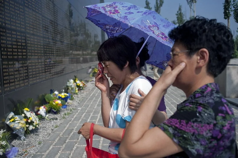 坐著輪椅的老人來到唐山地震紀念牆前為遇難的老伴獻花。（網絡圖片）