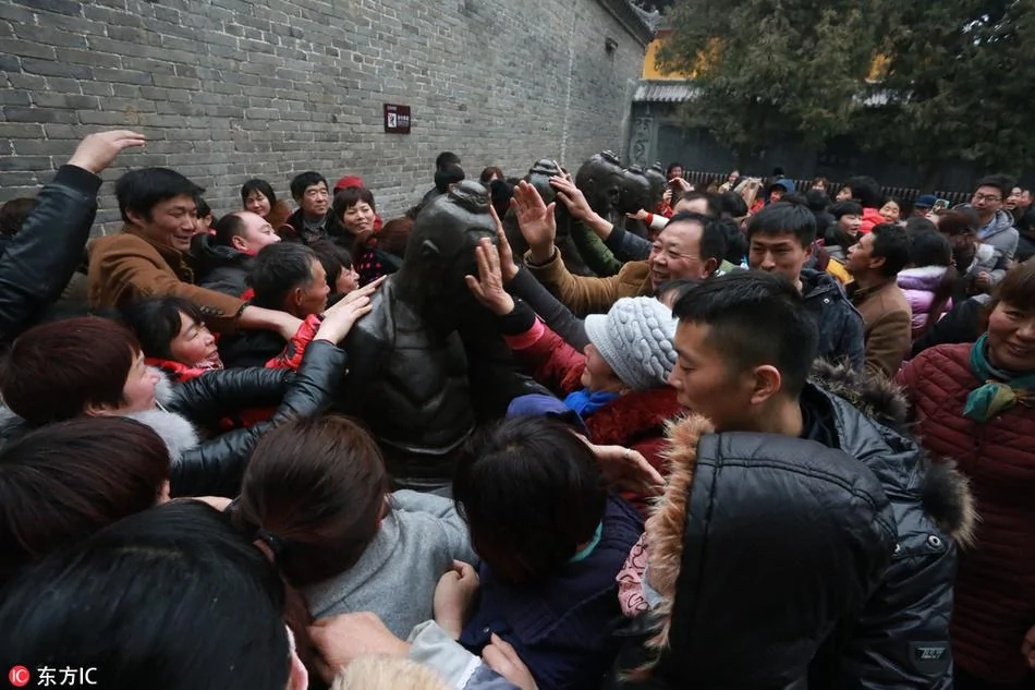 2017年1月28日，河南淮阳，在太昊陵烧新春第一香归来的民众来到岳飞观前排队伸手“打秦桧”。