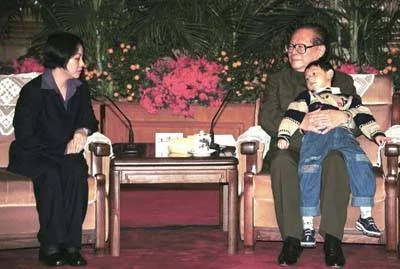 图为江泽民怀抱王伟6岁的儿子与王伟妻子阮国琴拍照