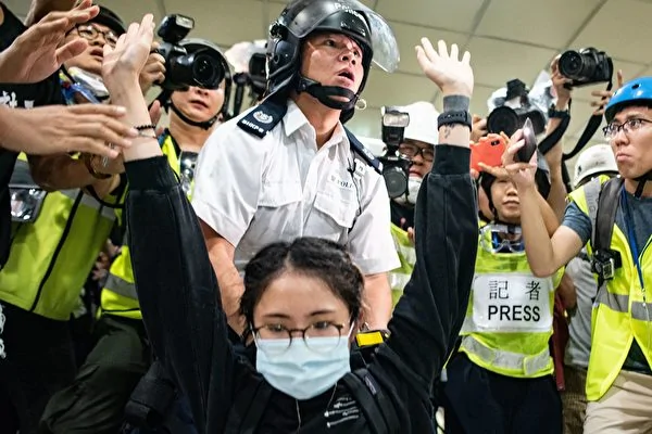 TOPSHOT - A protester gestures as a policeman looks on inside a shopping arcade in Sha Tin of Hong Kong after a rally against a controversial extradition law proposal in Sha Tin district of Hong Kong on July 14, 2019. - Riot police and protesters fought running battles in a Hong Kong shopping mall on July 14 night as unrest caused by a widely loathed plan to allow extraditions to mainland China showed no sign of abating. (Photo by Philip FONG / AFP) (Photo credit should read