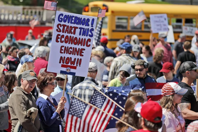 數以百計民眾在密蘇里州議會外舉牌示威，要求州長廢除居家避疫令，重啟經濟。(美聯社)