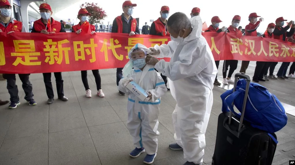 武漢解封，天河國際機場的旅客站在慶祝的標語橫幅旁。（2020年4月8日）