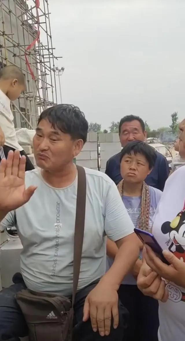 大衣哥耐心教村民唱歌 身后未建成小楼抢镜 唱歌干活两不误