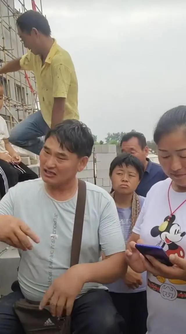 大衣哥耐心教村民唱歌 身后未建成小楼抢镜 唱歌干活两不误